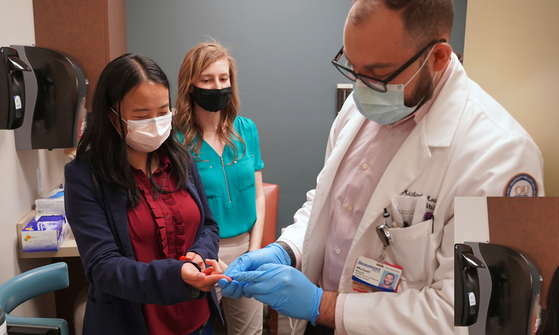 Michael Moussa (right), Tiffany Loh (left), and Sarah Provencher (center) demonstrate a finger stick blood test for volunteers at the student-run free clinic. (Photo by Andrew Dietderich)